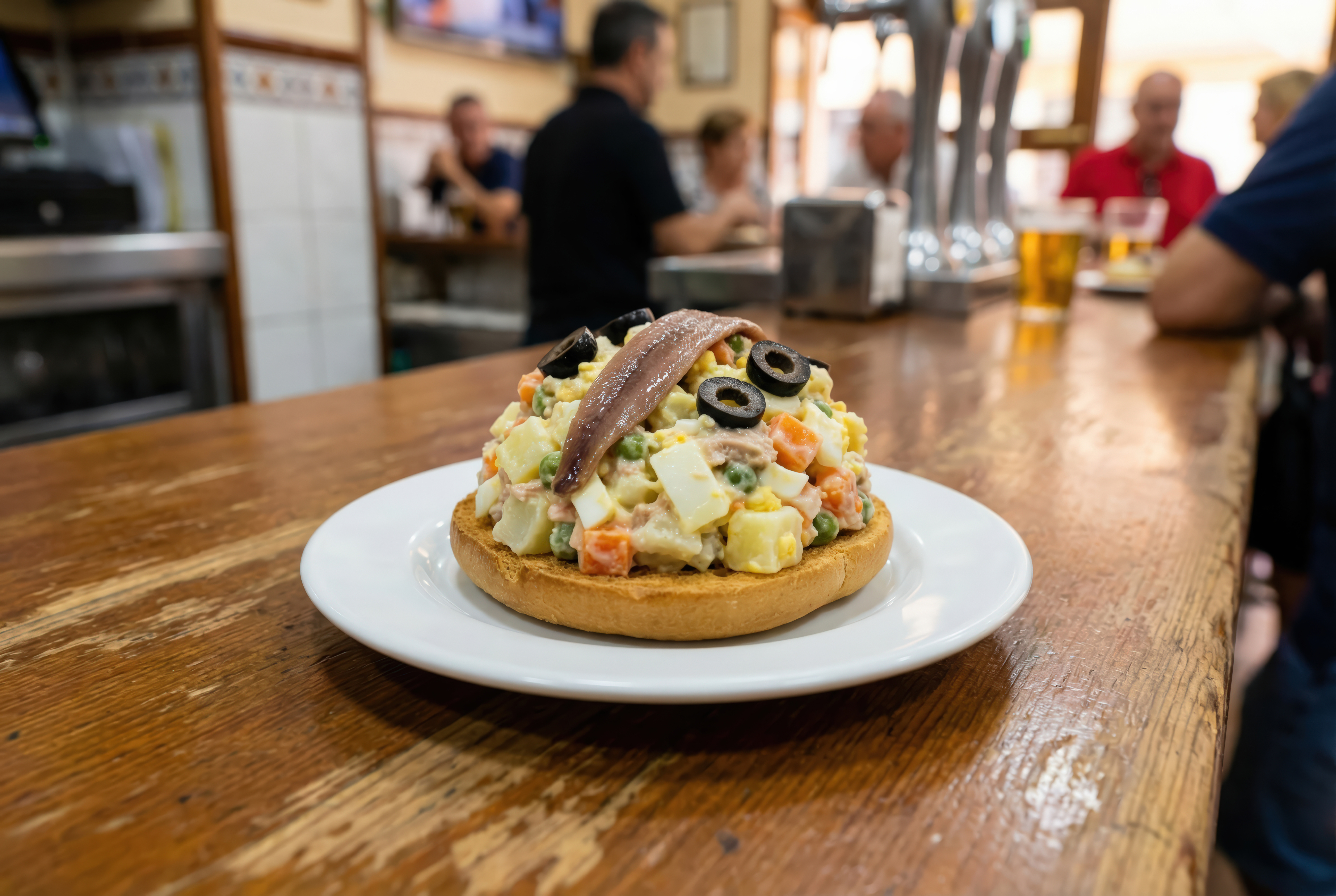 A classic Murcian marinera tapa, topped with ensaladilla rusa and anchovy, served at a traditional bar counter.
